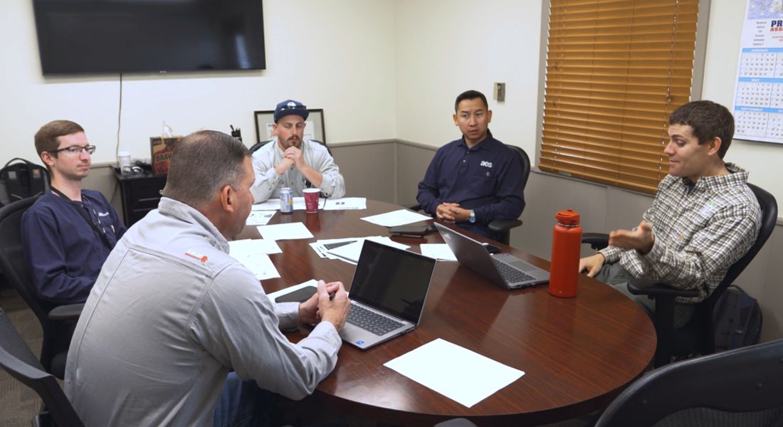 A working session around a conference table with laptops and notes