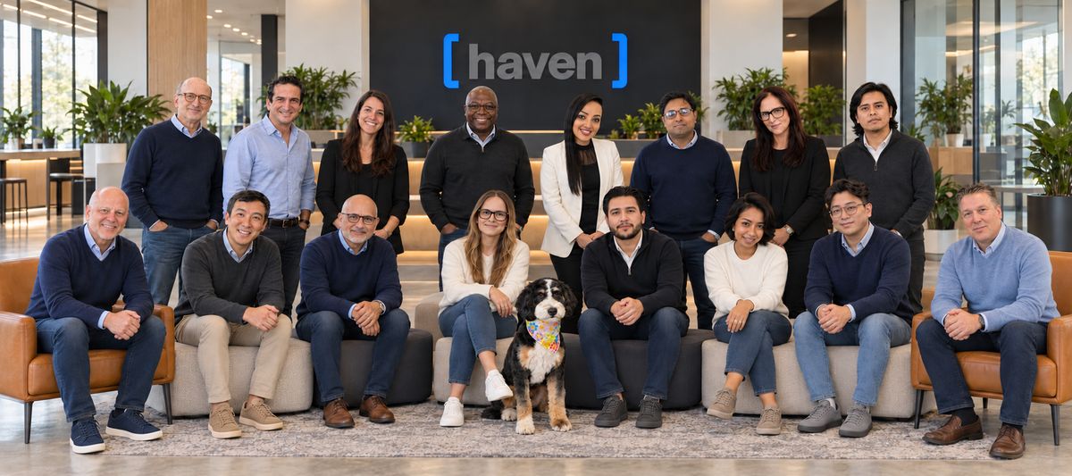 The Haven team gathered in an office lobby with the Haven sign behind them and a dog in a colorful bandana